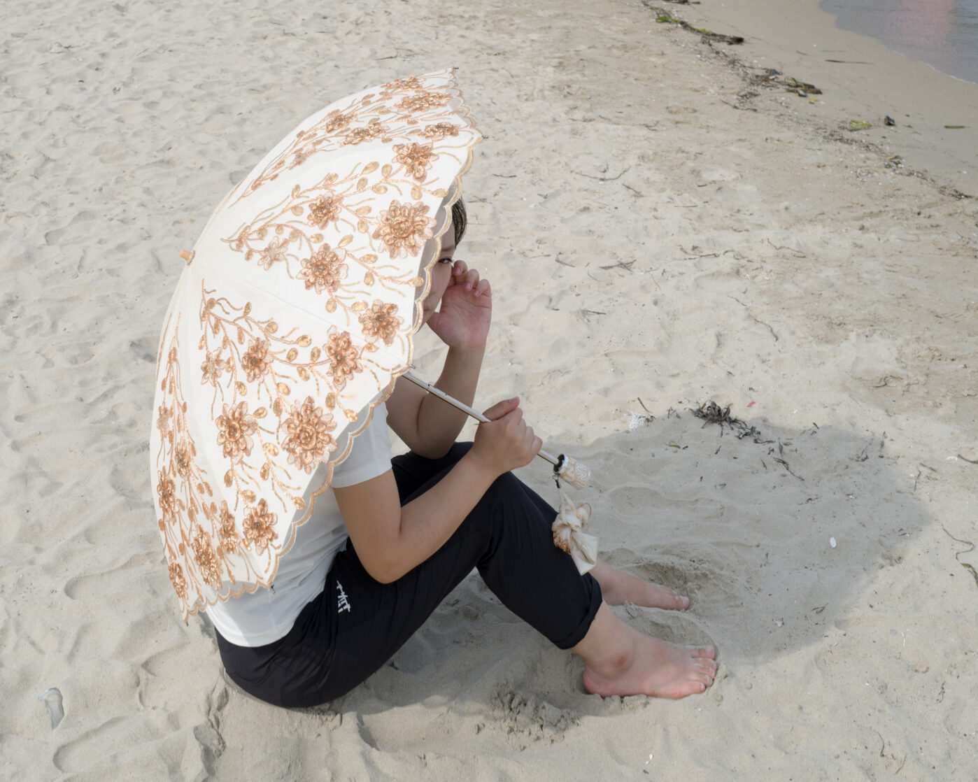 Девушка сидит под зонтиком у&nbsp;пляжа в&nbsp;Расоне, Северная Корея